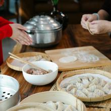 A photograph of two people making dumplings together