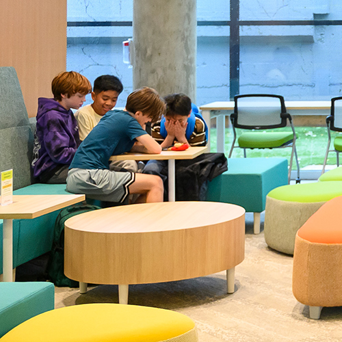 a group of tweens huddled around a table in the library's tween zone