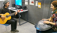 Two men playing guitar and handpan in the recording booth Two men playing guitar and handpan in the recording booth
