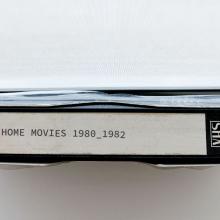 A photograph of a VHS tape with the label "Home Movies 1980_1982"