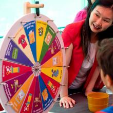 Minister Anne Kang spins a prize wheel at City Library's 2023 Summer Reading Club kickoff party