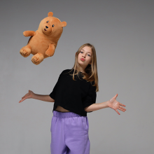 teen girl throwing a teddy bear up in the air