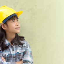 Young girl in construction hard hat looking to the side