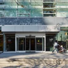 Front of library, showing the doors and a customer leaving.