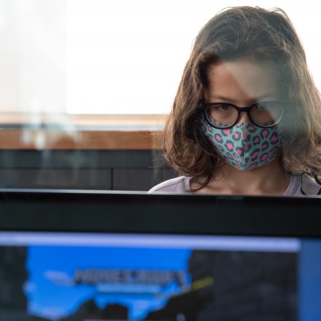 Minecraft kid Kid with mask on looking at computer screne