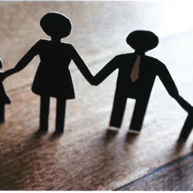 A family of four (mother, father, daughter, son) standing hand in hand made out of cardboard