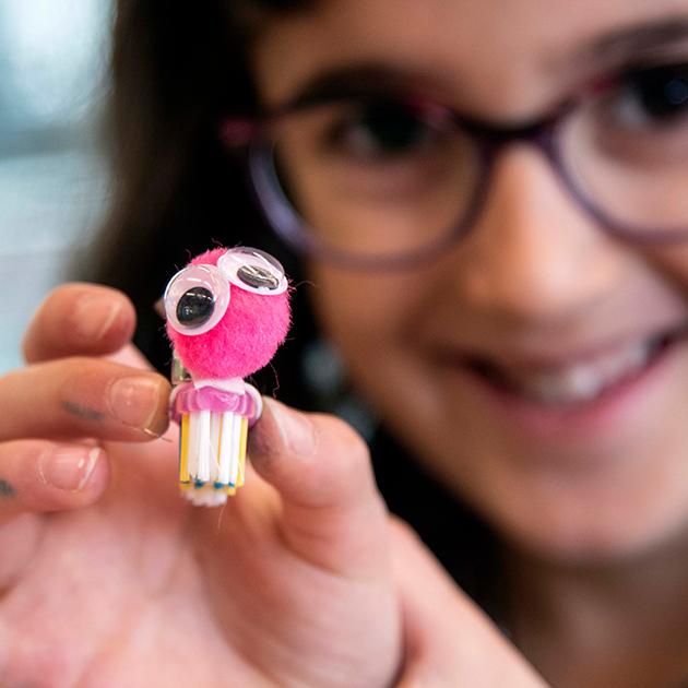 Build a bristlebot - a tiny robot made of common household items. bright pink bristlebot creation held by young girl