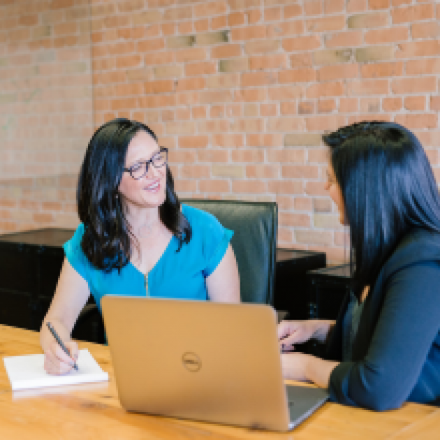 Two women having a meeting, with a laptop on the desk.