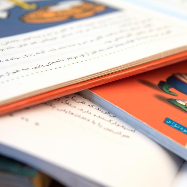 Colourful children's books open pages with text in Farsi