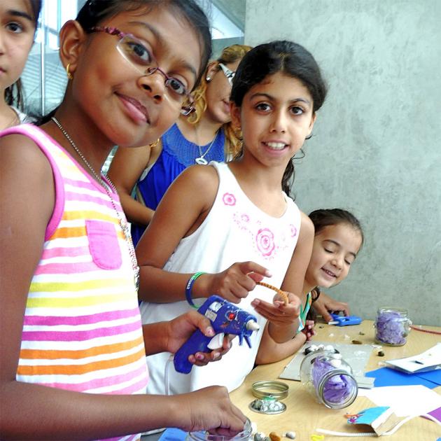 Children with glue gun, craft supplies, looking at camera smiling