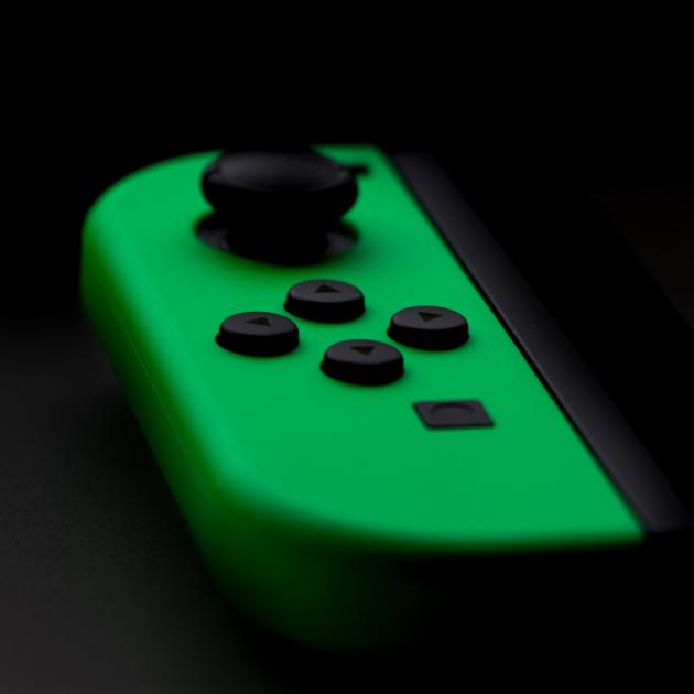 Lime green Switch controller with black buttons on a black background