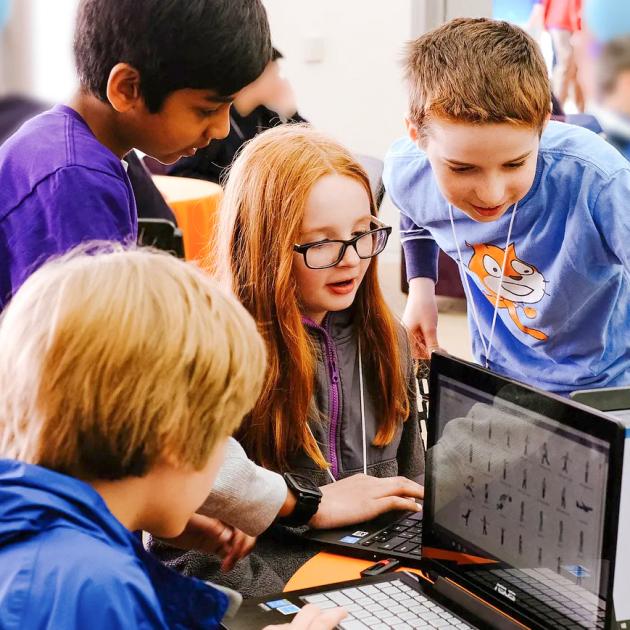 4 kids using a laptop computer to learn Scratch