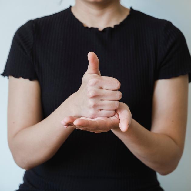 A fist with the thumb up placed in the palm of the left hand, which is the sign for help