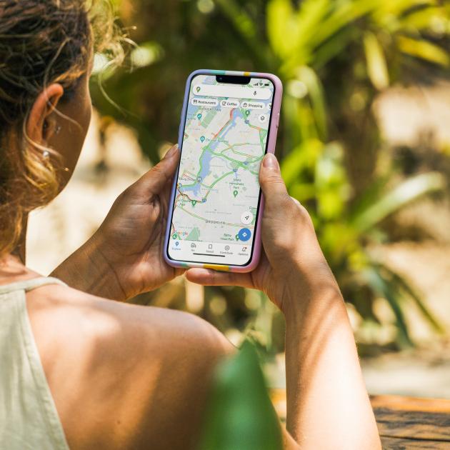 Wayfinding – Technology for travel and transportation Person holding iphone showing a map app, greenery in background.