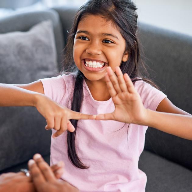 A young girl very enthusiastically is shown signing in American Sign Language
