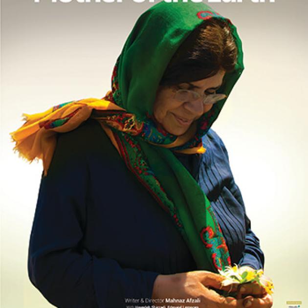 Pelan A woman wearing a scarf and glasses looking at a flower in her hands