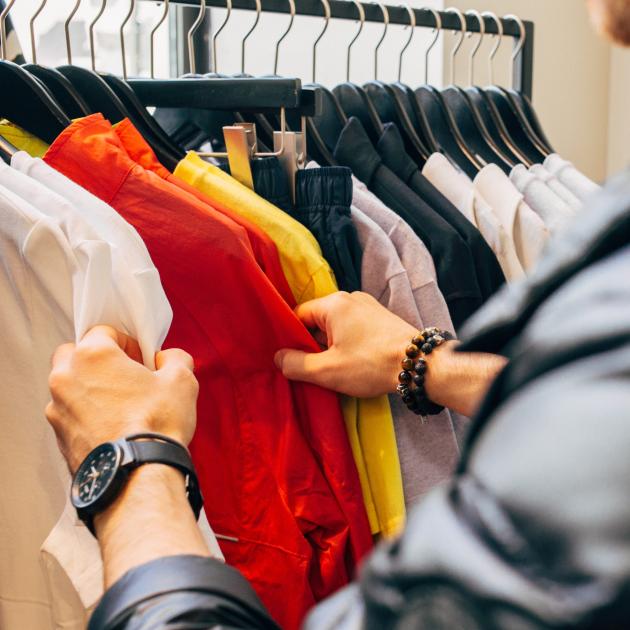 Shopping for shirts A person sorts through shirts on a clothing rack