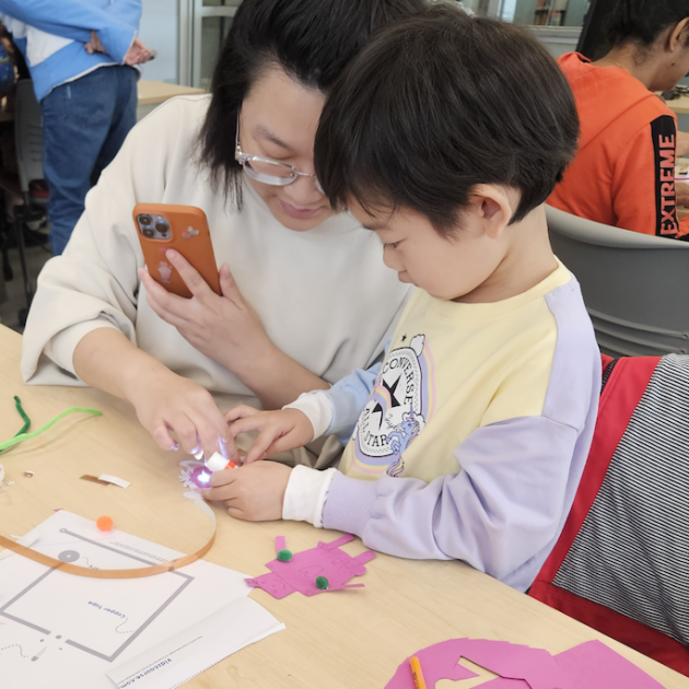 A mother and child are crafting a paper robot and circuit