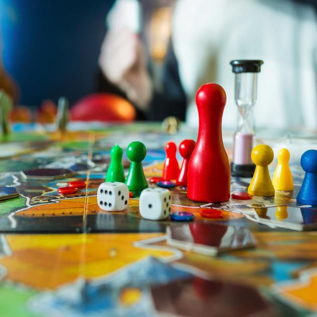 Board game night Board game with colourful pawns, timer and dice in foreground