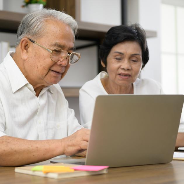 Seniors gathering Two seniors sitting at a table, looking at a laptop screen