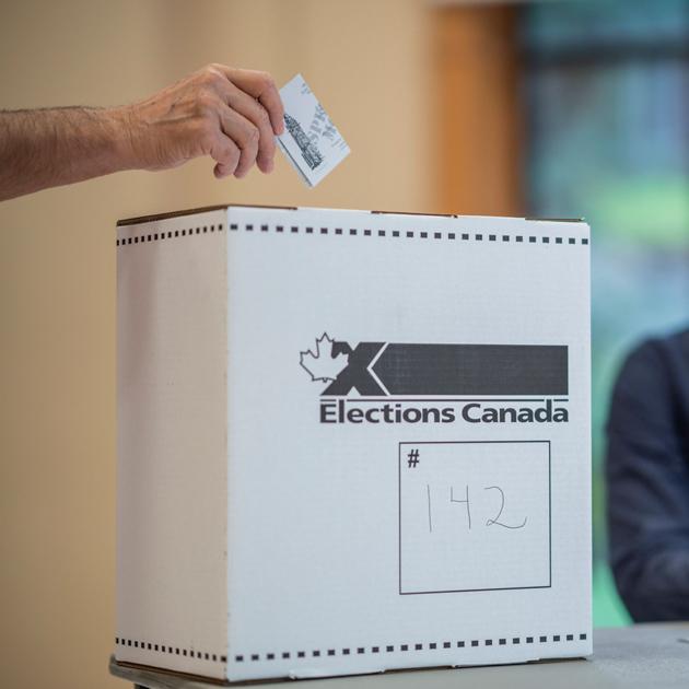 Elections Canada A photo of a person putting a ballot into a white Elections Canada box marked #142