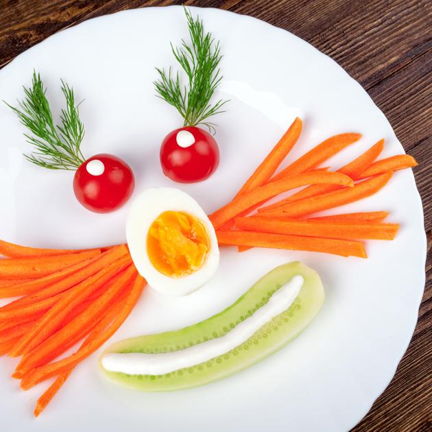 Tween snack attack Face on a plate made of carrots, boiled egg, tomatoes, herbs