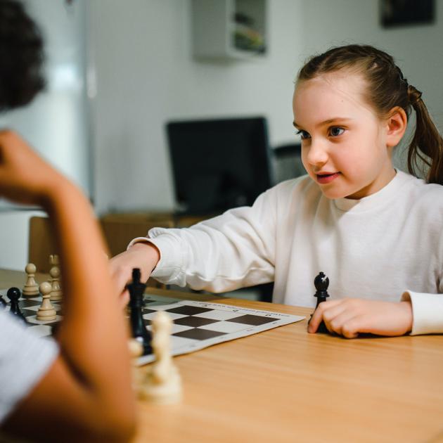 Kids chess club Children playing chess, one making a move and looking at the other