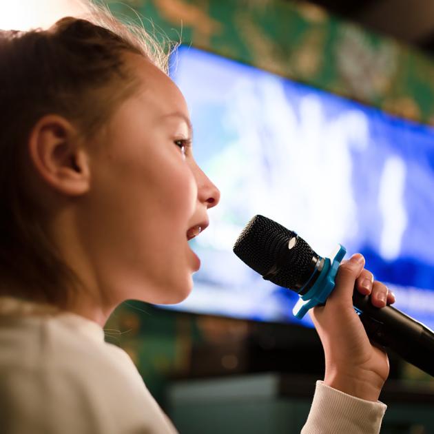 Tween karaoke party Tween child holding microphone with screen in background