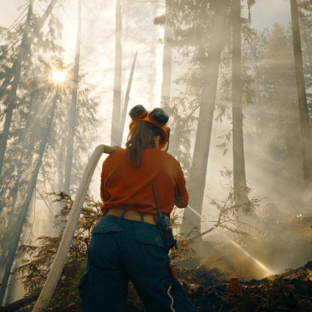 A firefighter hoses down a forest fire in the Kootenays