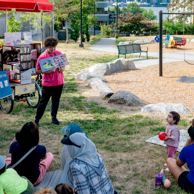 Staff member presenting a storytime in a park Staff member presenting a storytime in a park