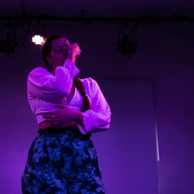 A woman dances in a purple-coloured room