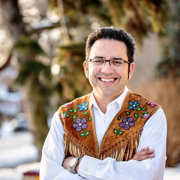 Author standing in snowy suburb with traditional indigenous hide and beaded vest on