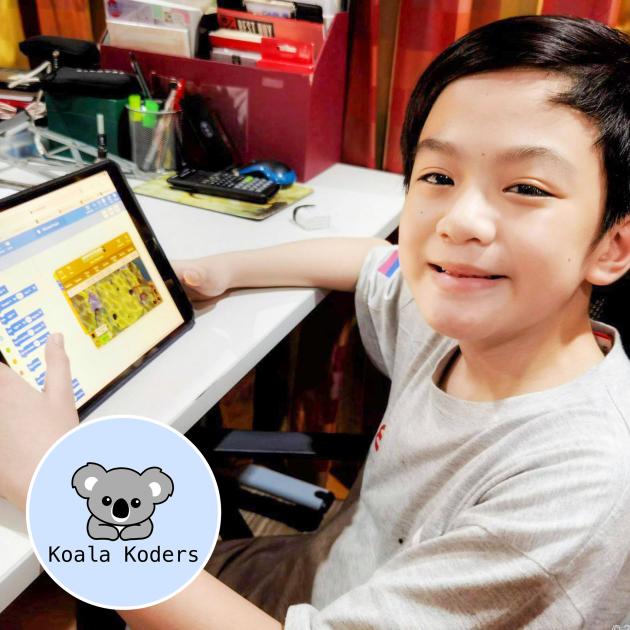 VR robotics with Koala Koders Child holds tablet with coding program, looks to camera smiling