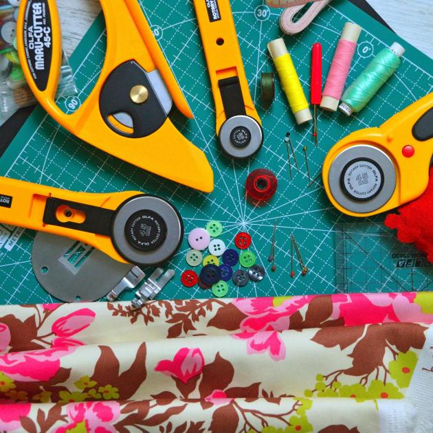 Sewing tools and notions displayed around a green cutting mat.