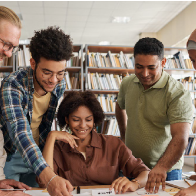 Five people standing and sitting around a table studying