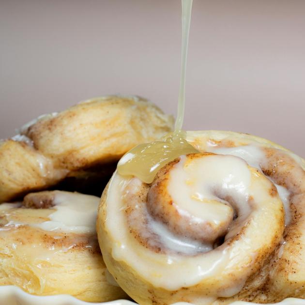 Cinnamon buns getting icing poured on