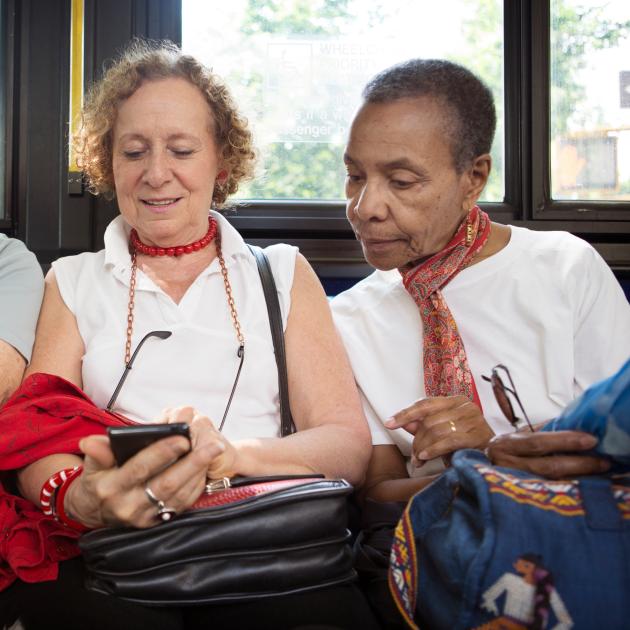 Two senior ladies looking at a cellphone on the bus