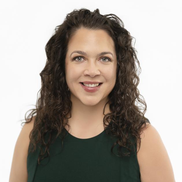Jennifer Hufnagel, consultant, looks into the camera smiling, with long wavy brown hair and a black top.