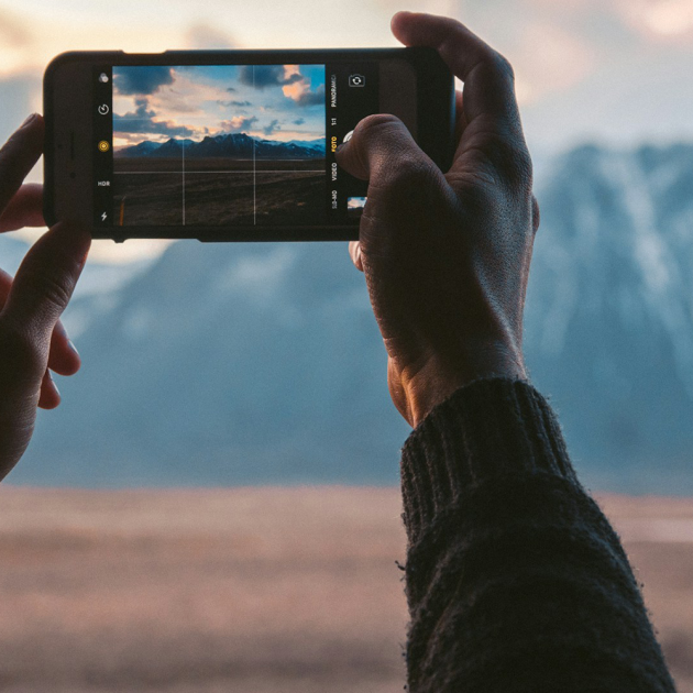 Person taking a photograph of a distant mountain using their phone