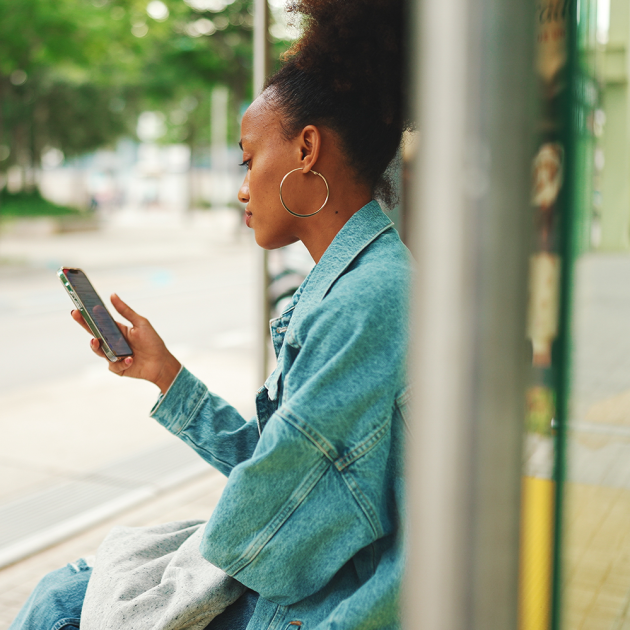 a woman at a bus stop looking at her phone