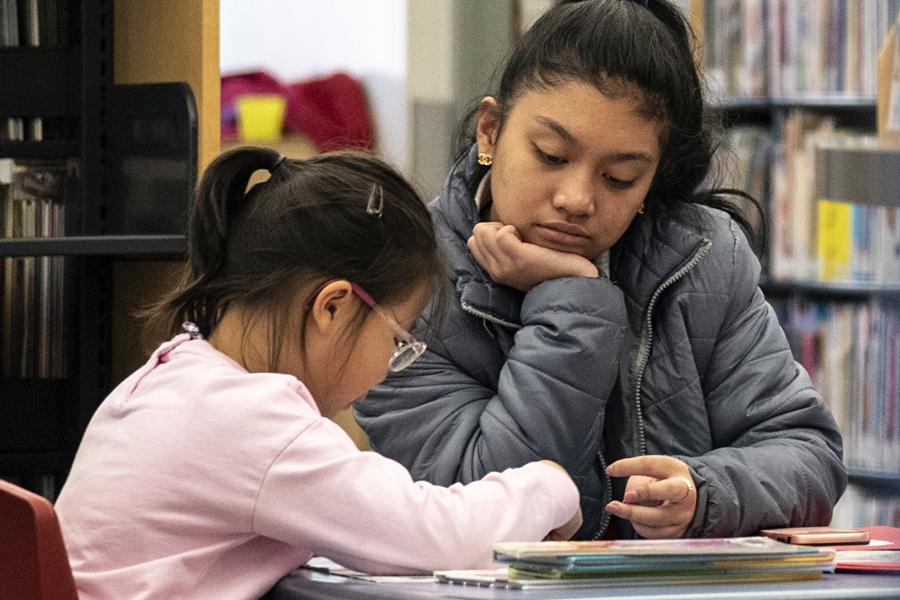 Teen helping a child read