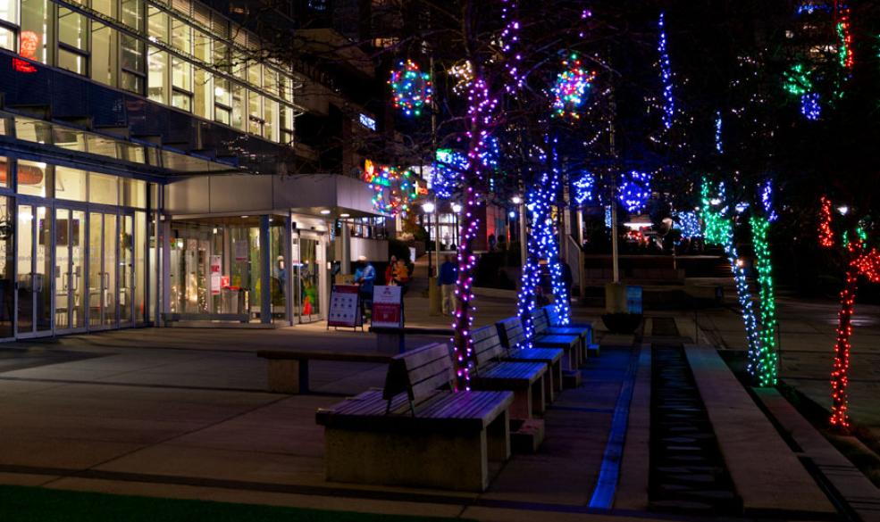 Photo of Civic Plaza at night with holiday lights and the library building in the background.