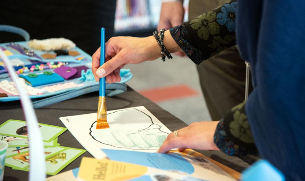 A person is holding a paintbrush and painting on a reusable mat