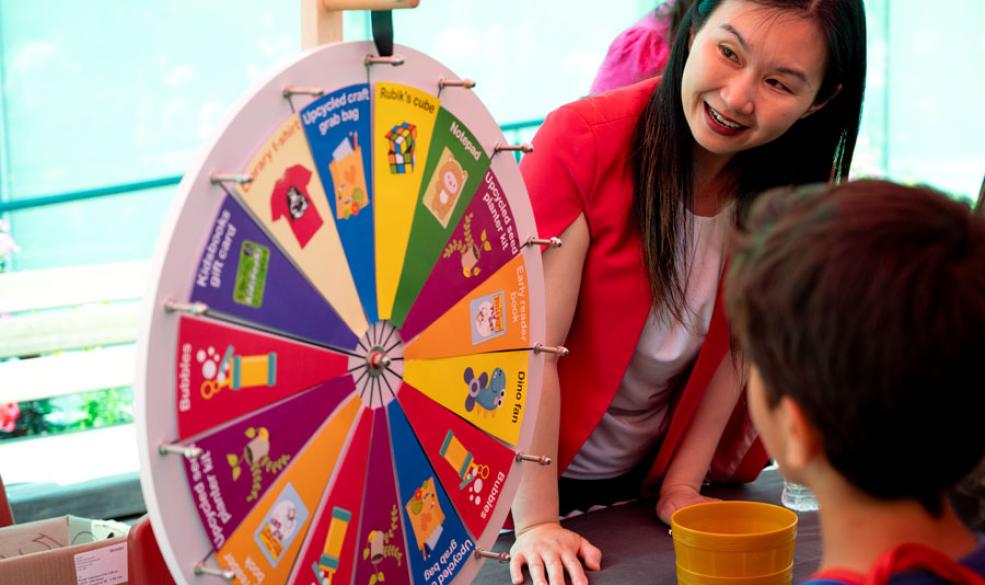 Minister Anne Kang spins a prize wheel at City Library's 2023 Summer Reading Club kickoff party