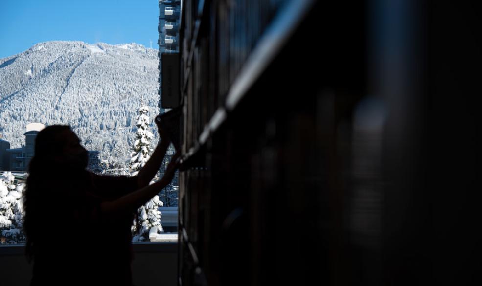 A silhouette image of someone putting a book on the shelf with a snowy mountain in the background