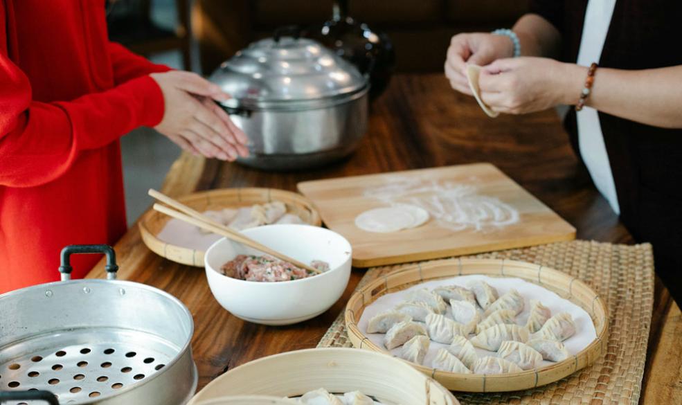 A photograph of two people making dumplings together