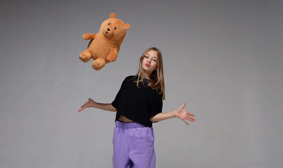teen girl throwing a teddy bear up in the air