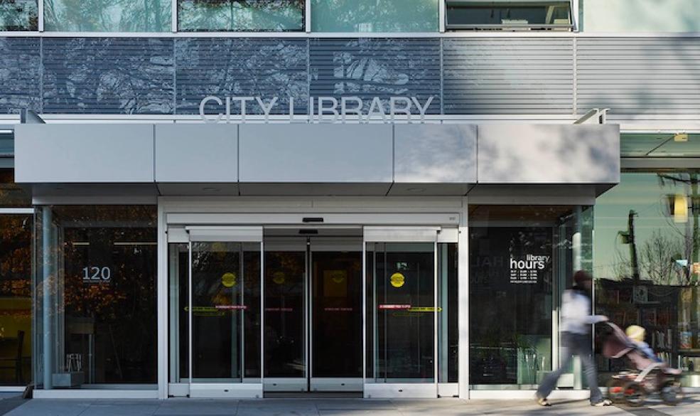 Front of library, showing the doors and a customer leaving.
