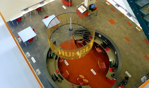 Top view of hanging circular sculpture with text illuminated on it 