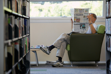 Man reading newspaper at the library